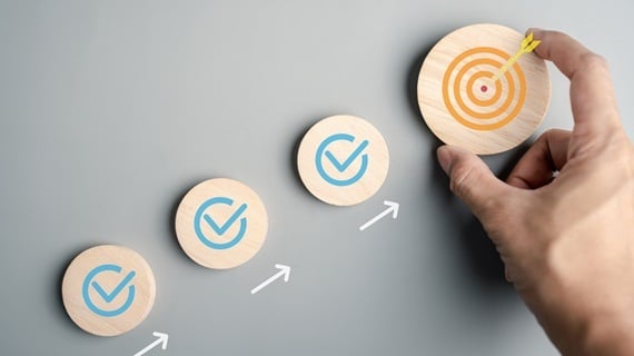 Check-marked discs advancing upward to a marked target